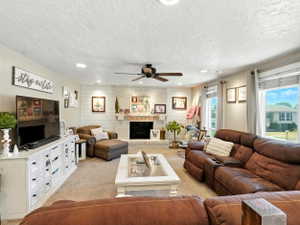 Living area with recessed lighting, light colored carpet, a ceiling fan, a textured ceiling, and a brick fireplace