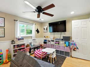 Playroom featuring wainscoting, light wood-style floors, a ceiling fan, and recessed lighting