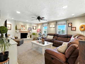 Living room with recessed lighting, a textured ceiling, ceiling fan, carpet, and a fireplace
