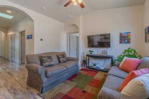 Living area with arched walkways,  vaulted ceiling, and a ceiling fan