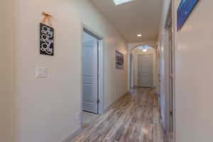 Hall with arched walkways, dark wood finished floors, and recessed lighting
