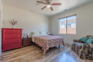 Primary bedroom with wood finished floors and a ceiling fan