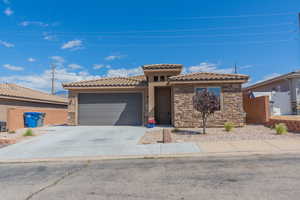 Mediterranean / spanish-style home featuring stone siding, concrete driveway, a garage, and a tile roof