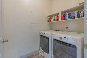 Laundry area with washer and clothes dryer and light wood-style flooring
