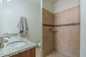 Bathroom featuring tiled shower and double vanity