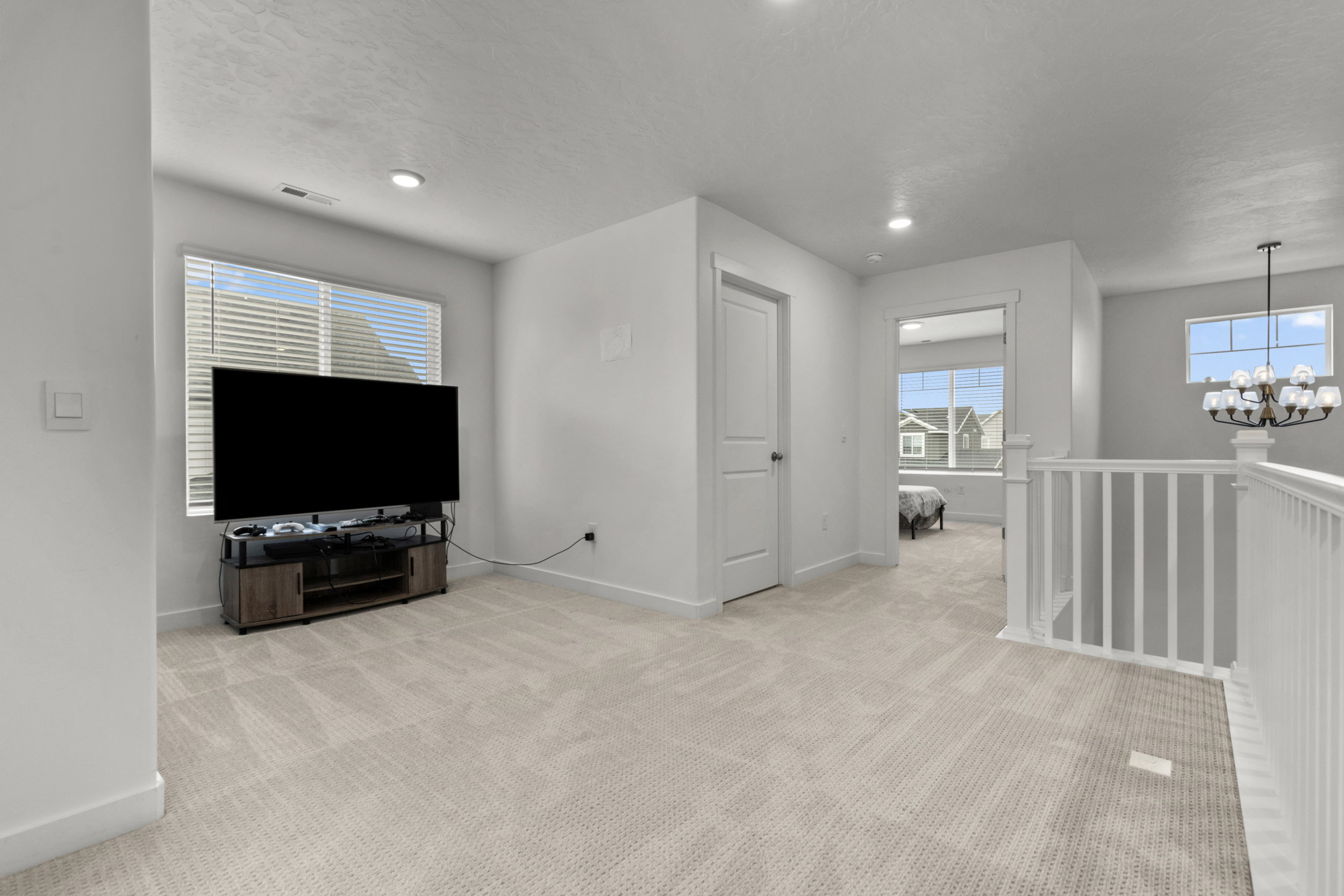 Unfurnished living room featuring a chandelier and light colored carpet