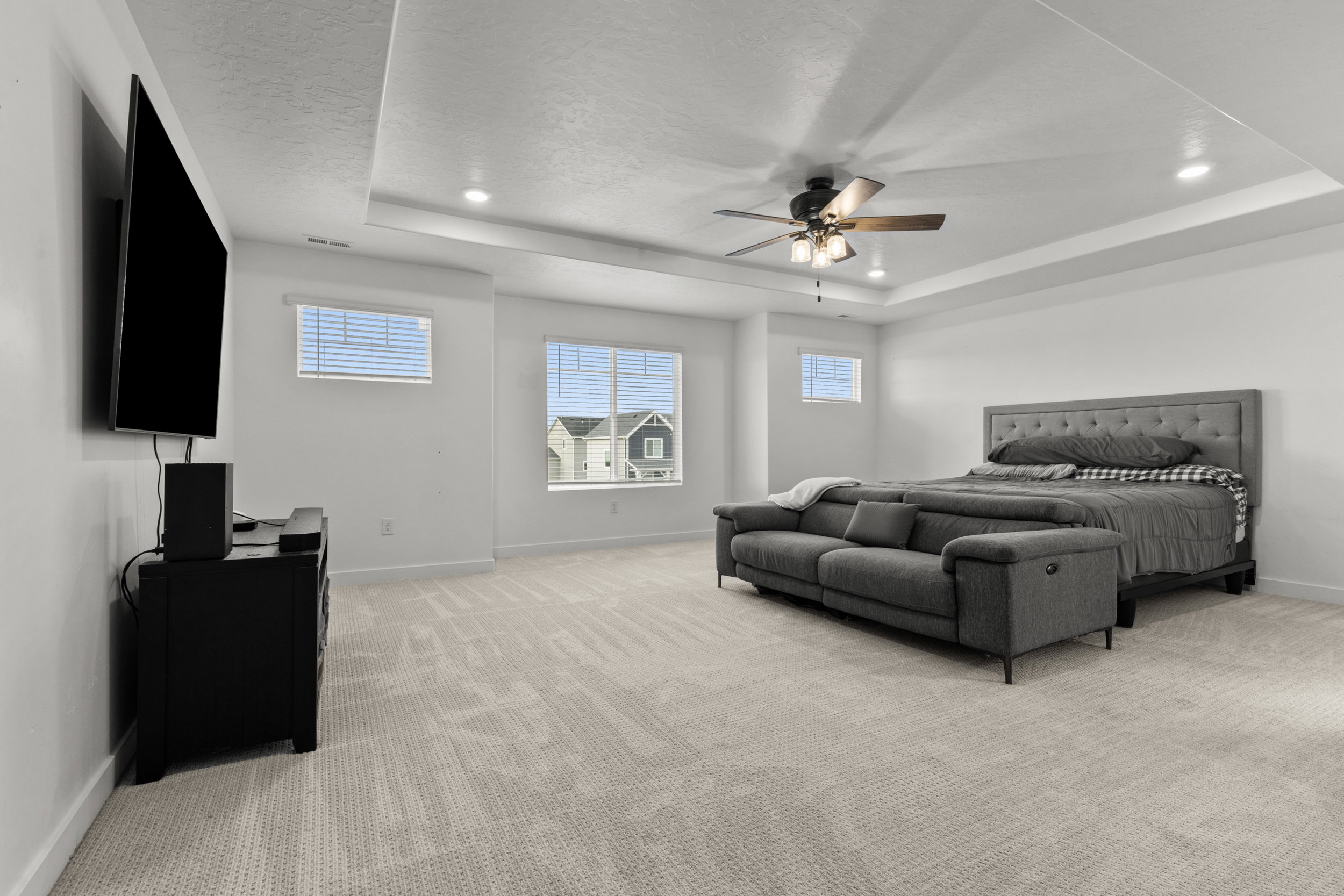 Bedroom featuring light carpet, a ceiling fan, and a tray ceiling
