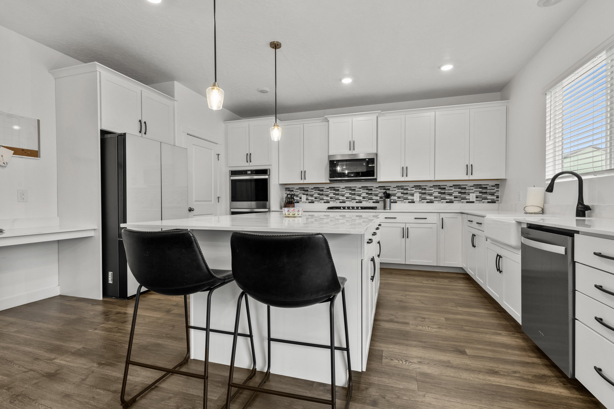Kitchen with a kitchen bar, a center island, stainless steel appliances, white cabinetry, and light stone countertops