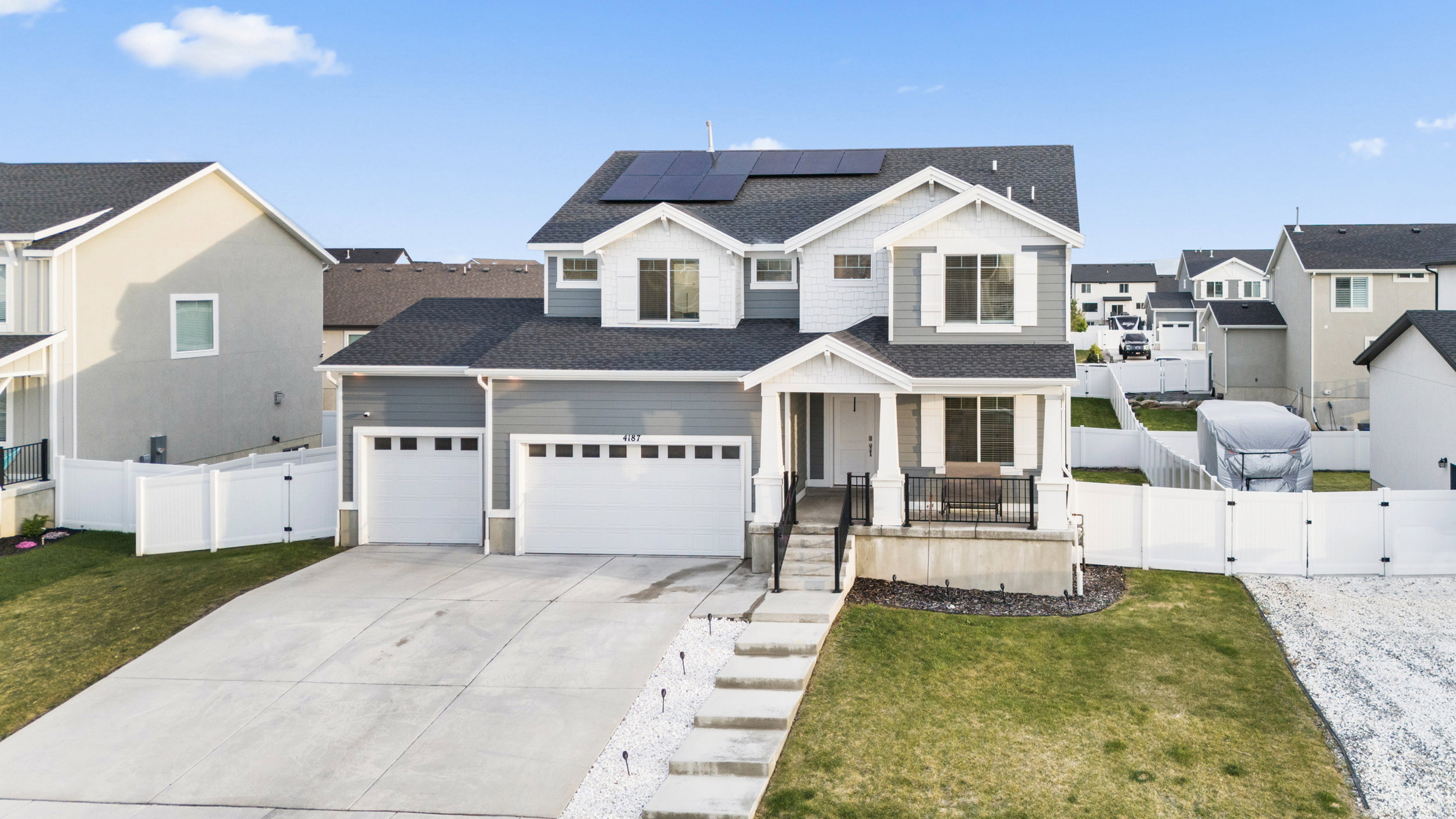 View of front facade with a gate, covered porch, roof mounted solar panels, and a residential view