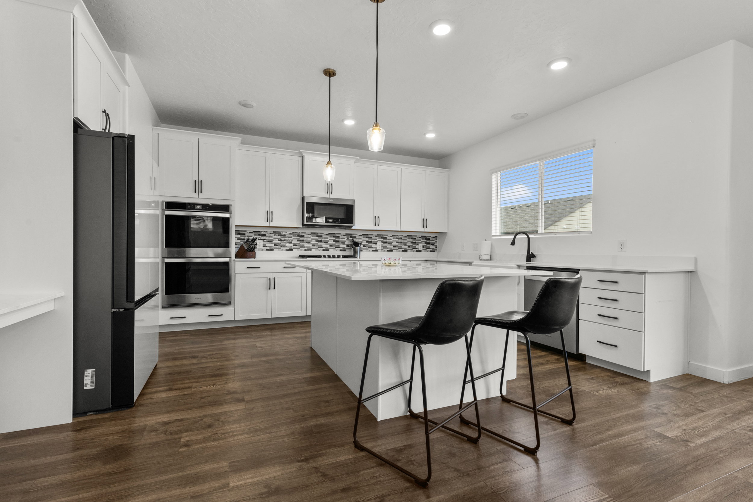 Kitchen featuring a breakfast bar, white cabinets, a kitchen island, stainless steel appliances, and decorative light fixtures