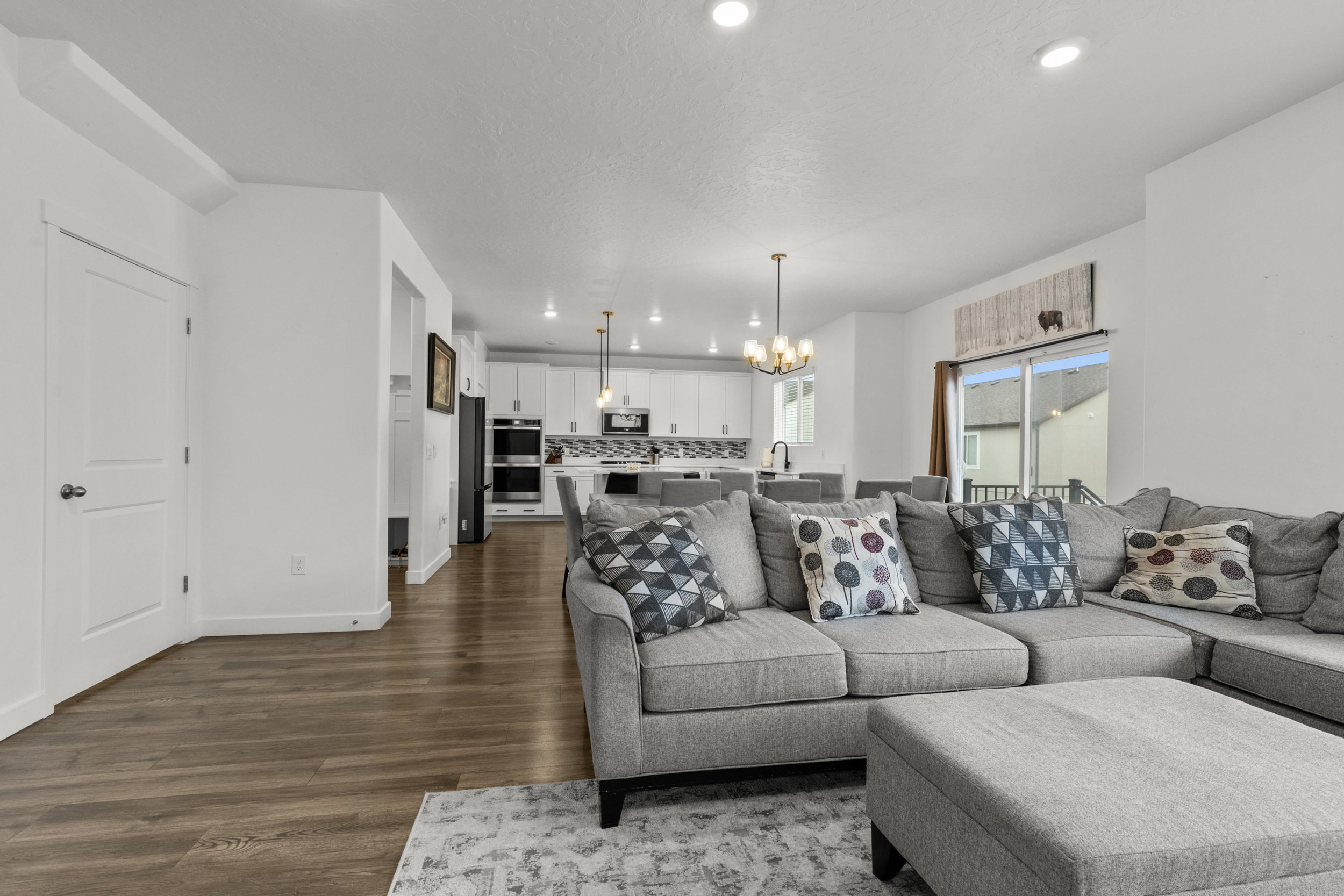 Living room with suspended lighting and dark wood-type flooring