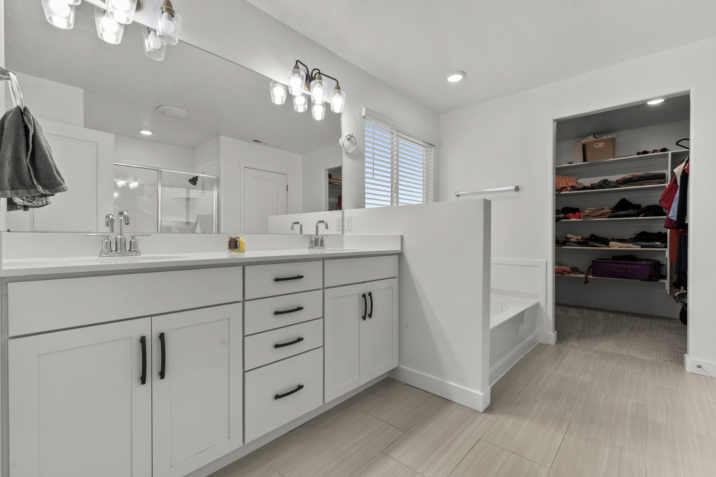Bathroom featuring a spacious closet, double vanity, a stall shower, and recessed lighting