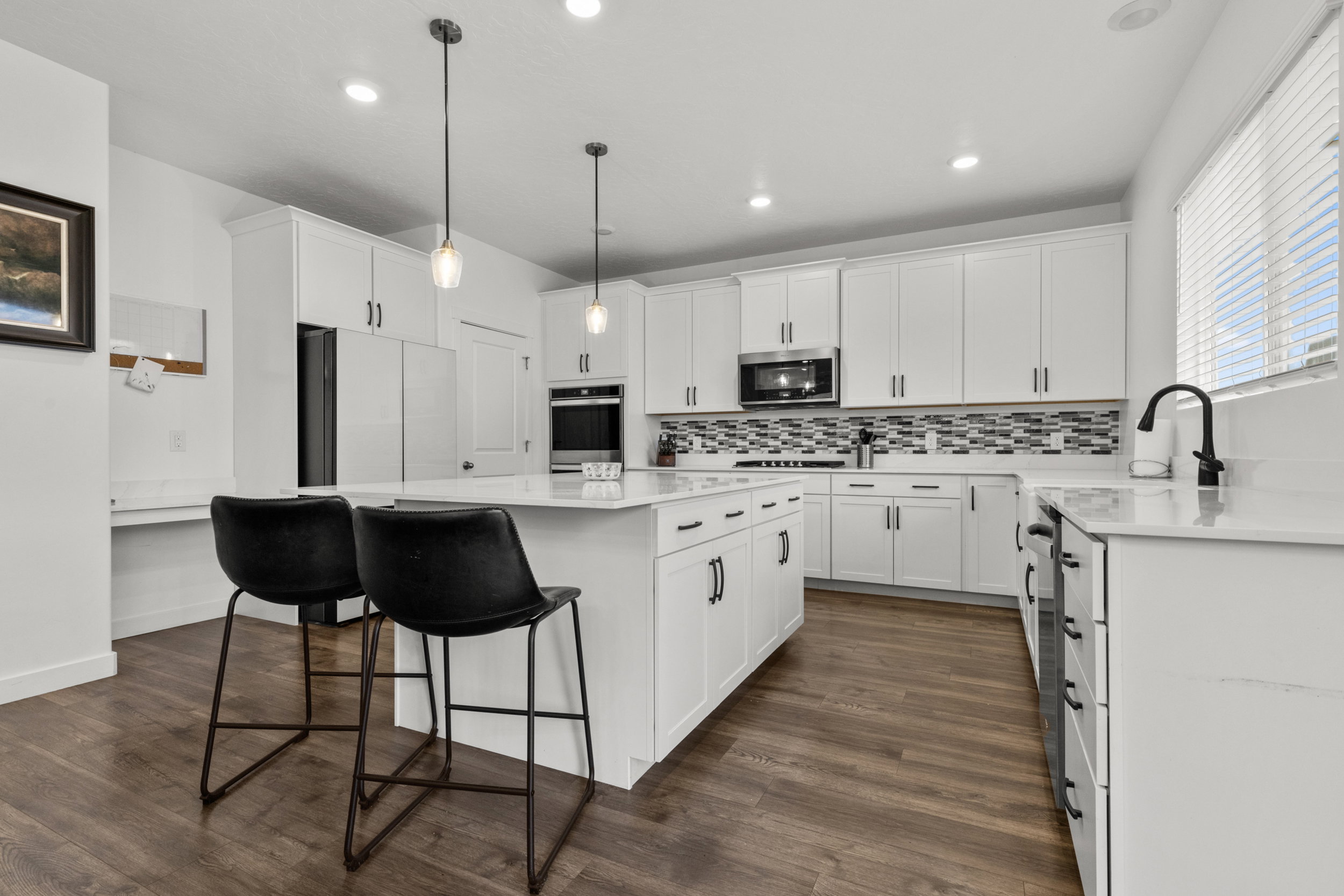 Kitchen with a kitchen island, a breakfast bar, light stone countertops, white cabinets, and decorative light fixtures