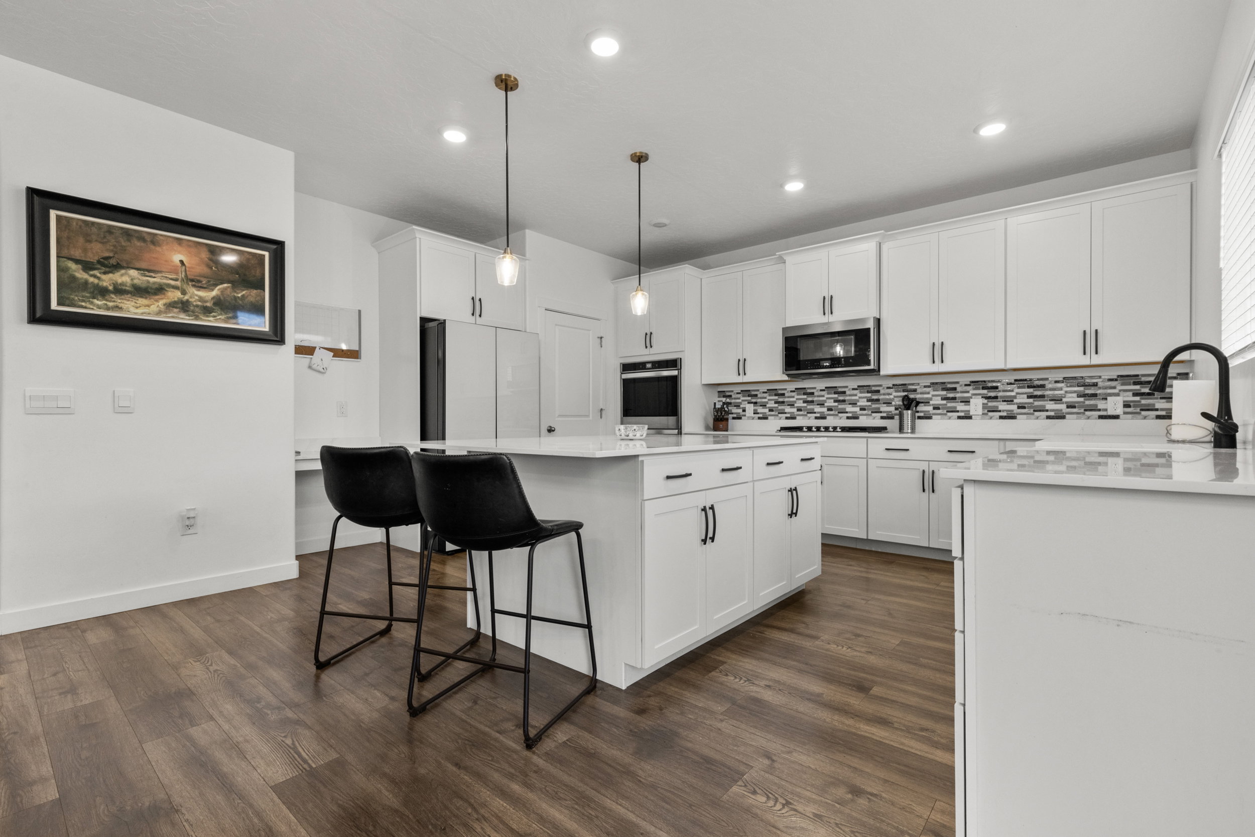 Kitchen with a breakfast bar, a kitchen island, white cabinetry, pendant lighting, and backsplash