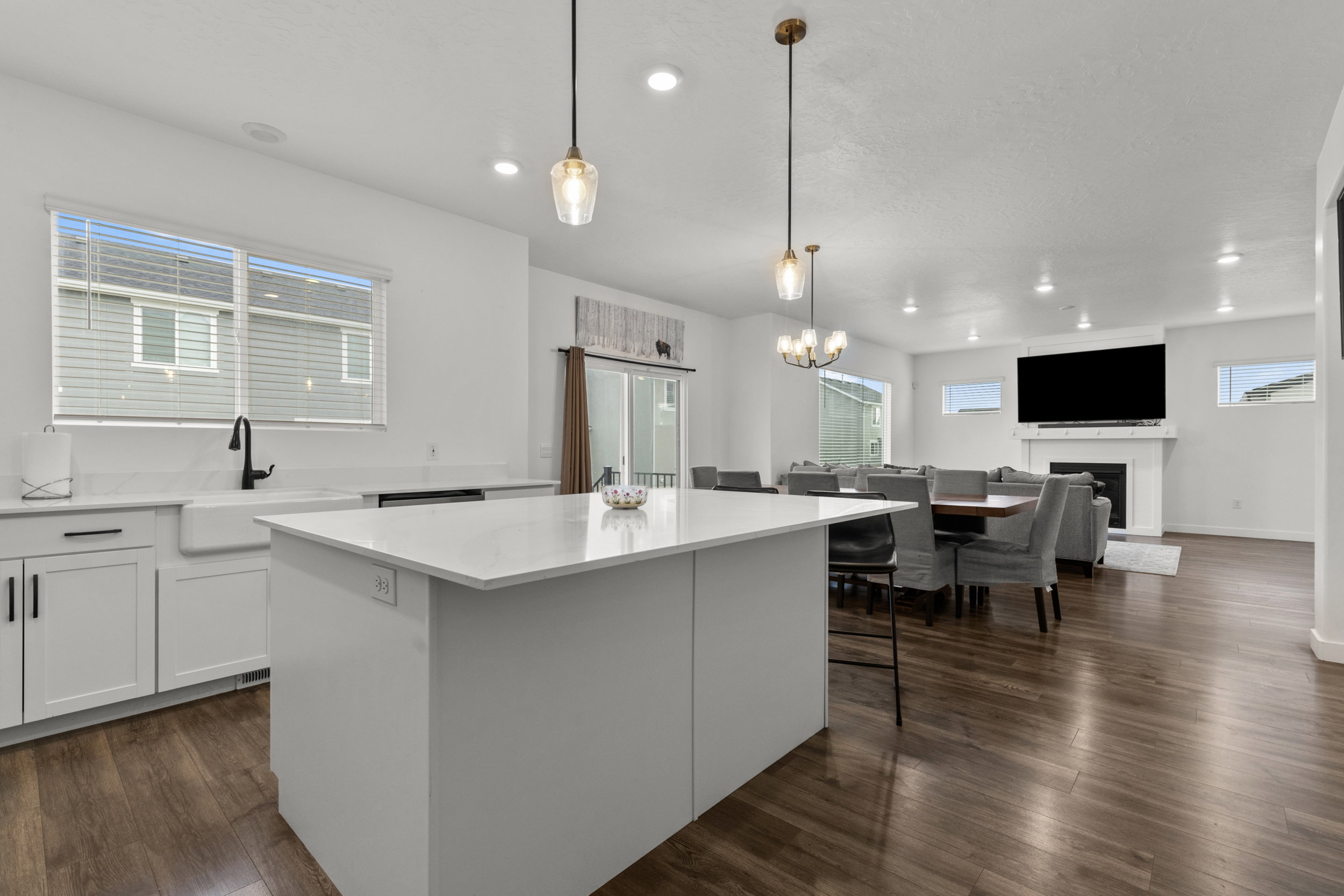 Kitchen with a center island, dark wood-style floors, white cabinetry, light stone counters, and a kitchen breakfast bar