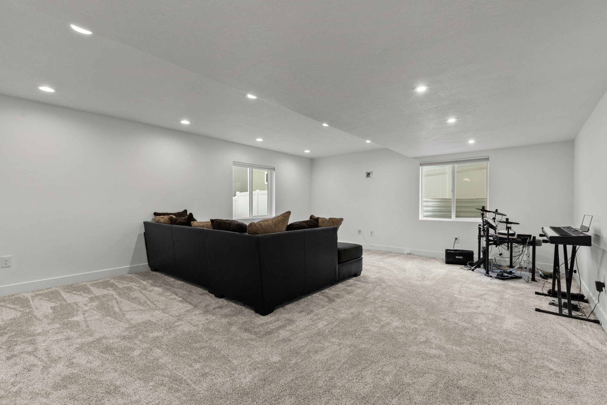 Living area with light carpet and recessed lighting