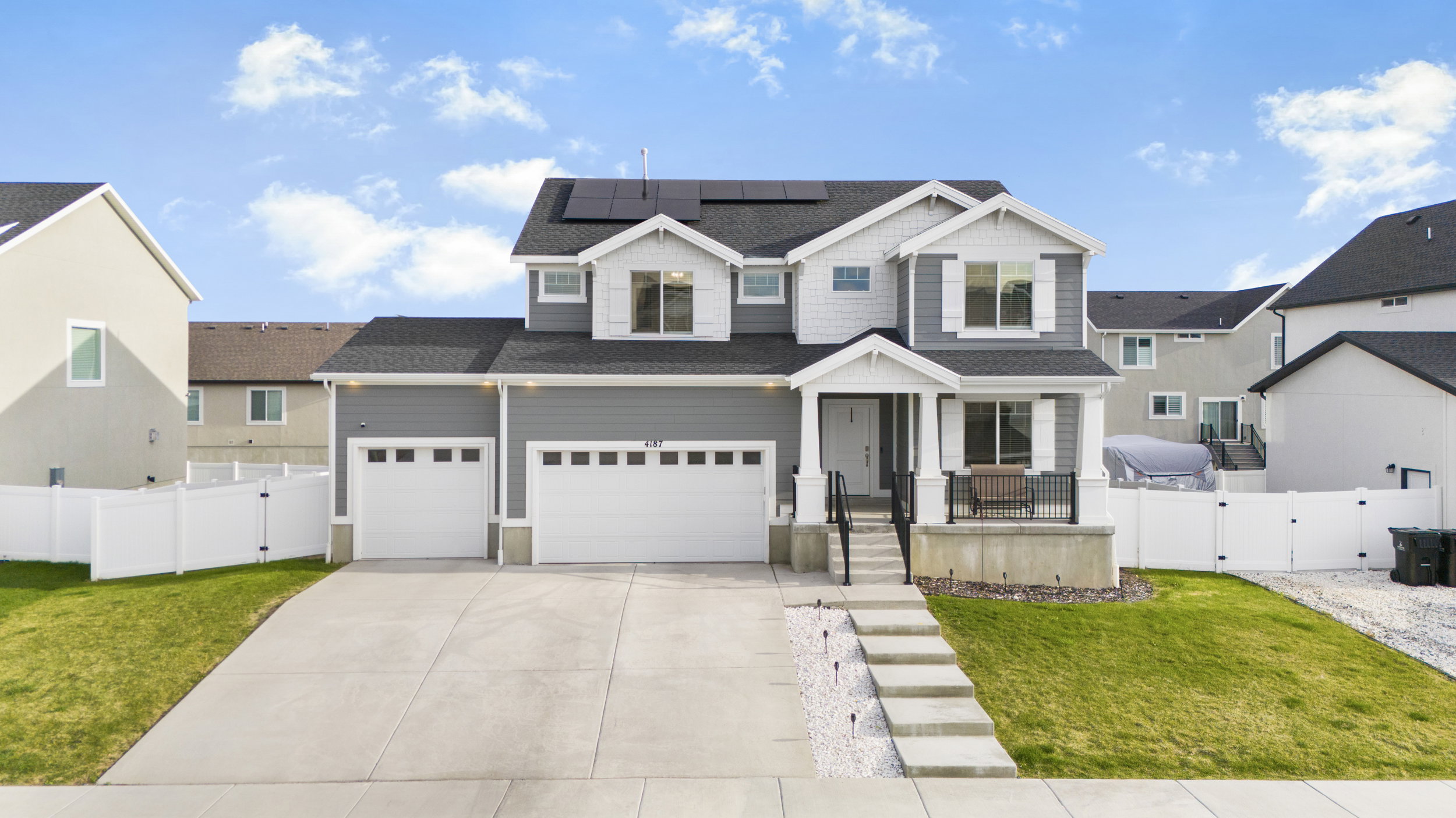 View of front of home featuring a gate, solar panels, driveway, a shingled roof, and a garage