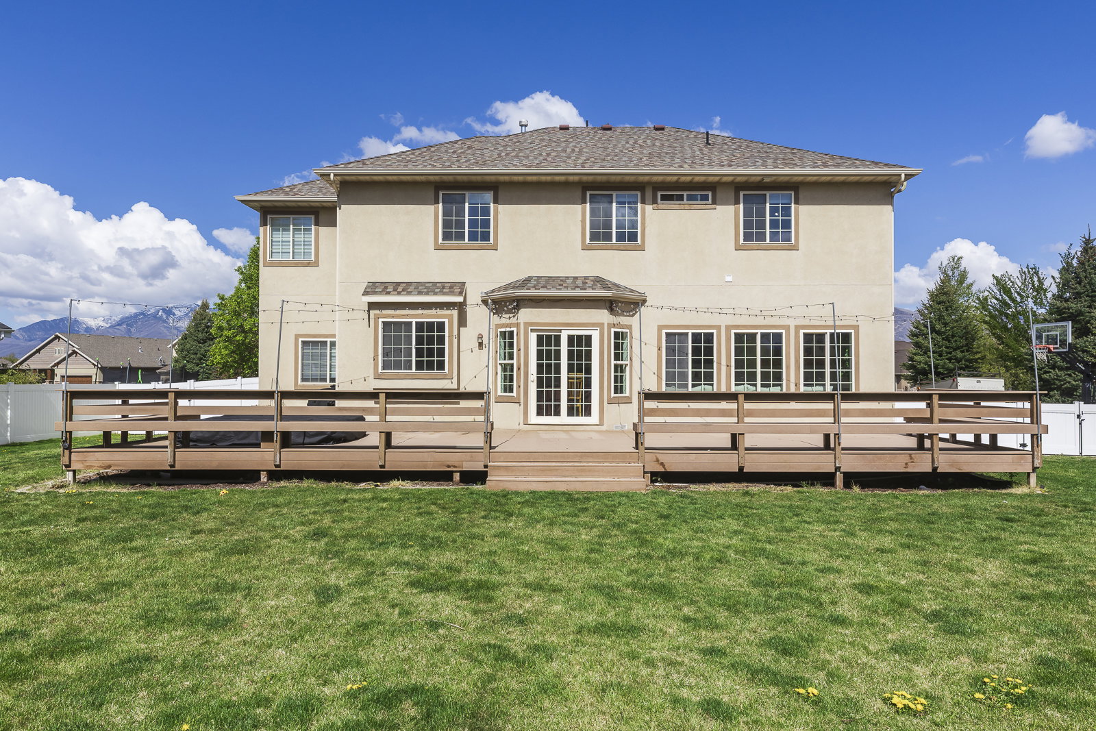 Rear view of property featuring a deck with mountain view, stucco siding, and a shingled roof