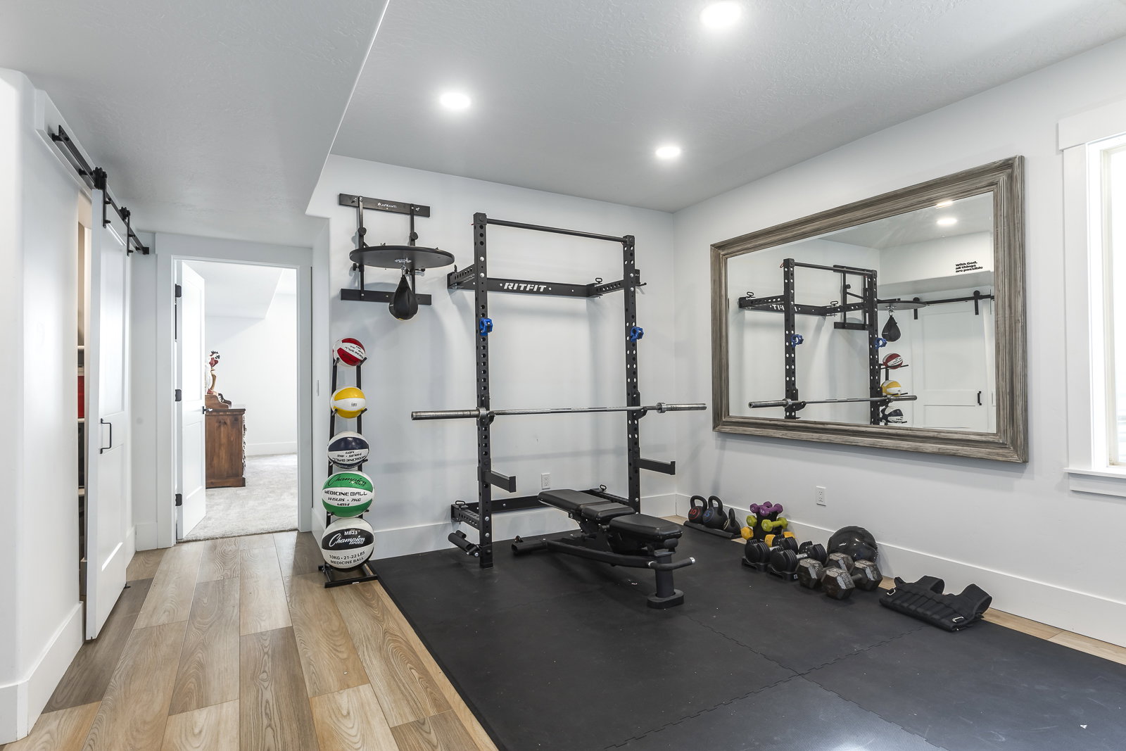 Workout room with light wood-style flooring, a barn door, and recessed lighting