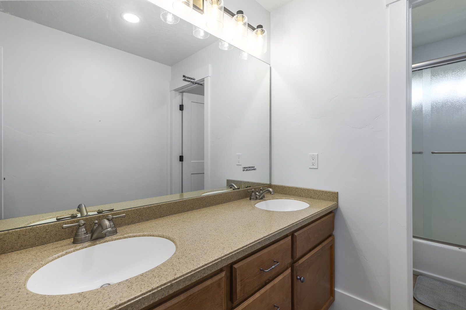 Bathroom featuring double vanity and bath / shower combo with glass door