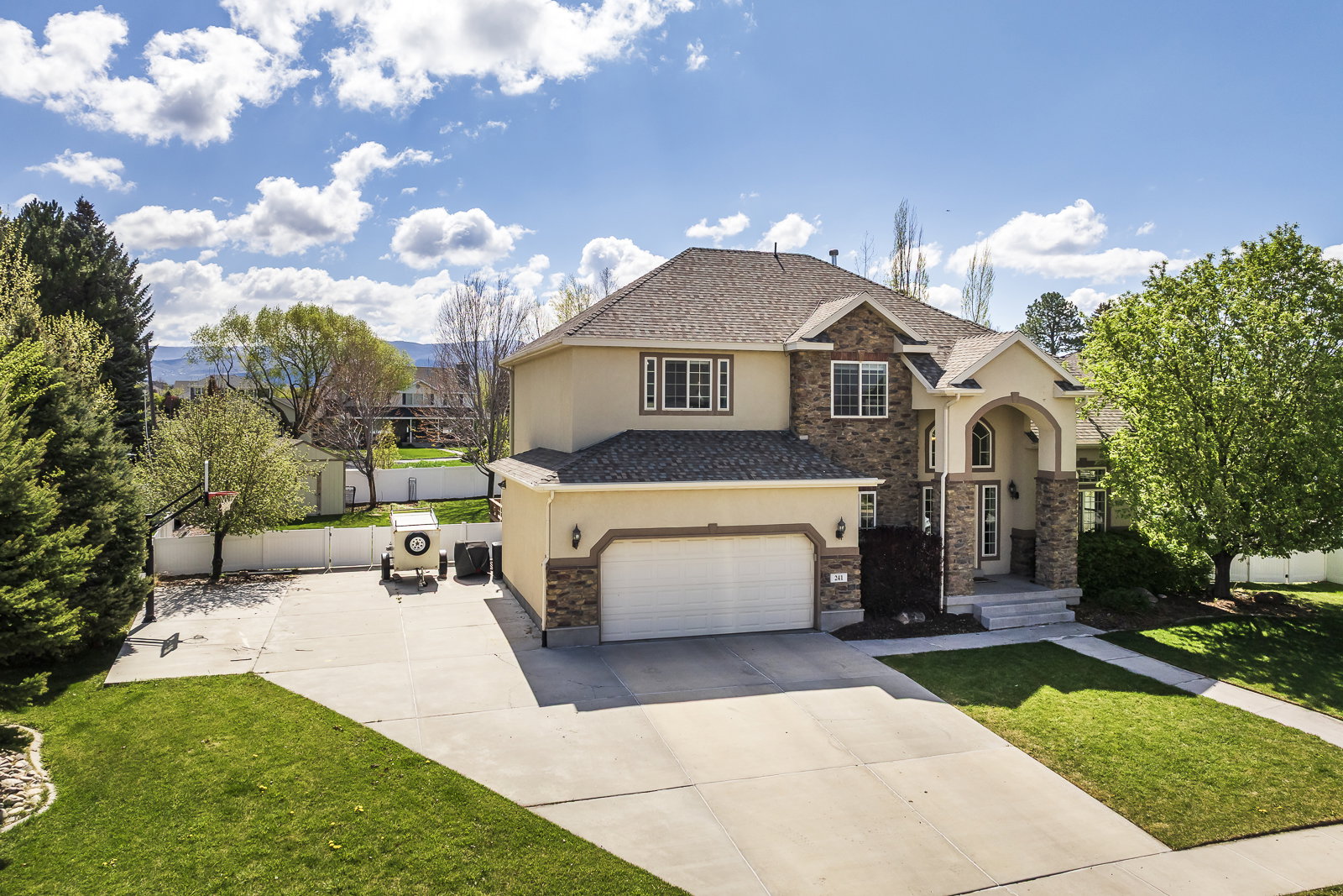Traditional home featuring stucco siding, driveway, stone siding, and a garage