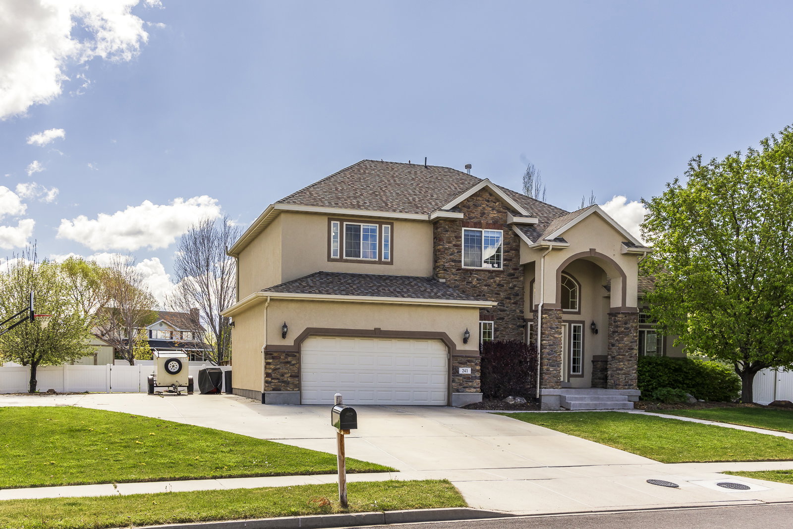 View of front of house featuring stucco siding, concrete driveway, stone siding, an attached garage, and roof with shingles