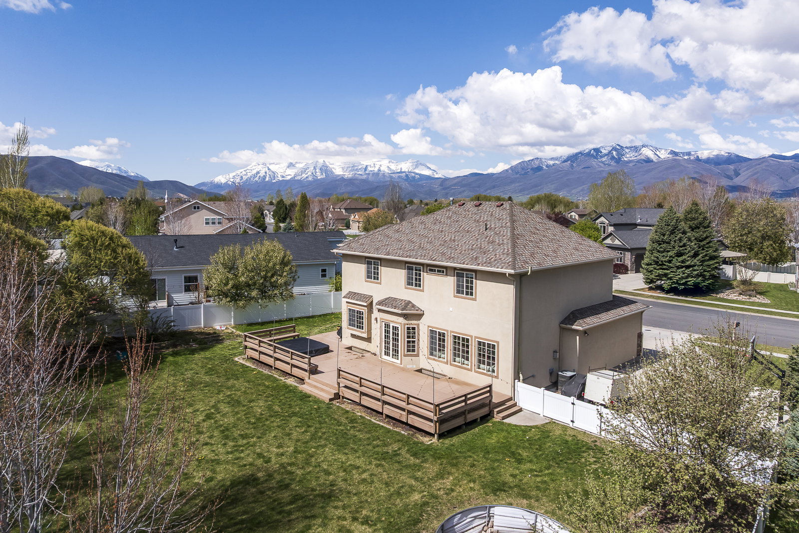 Rear view of house with a fenced backyard, stucco siding, a deck with mountain view, french doors, and a shingled roof