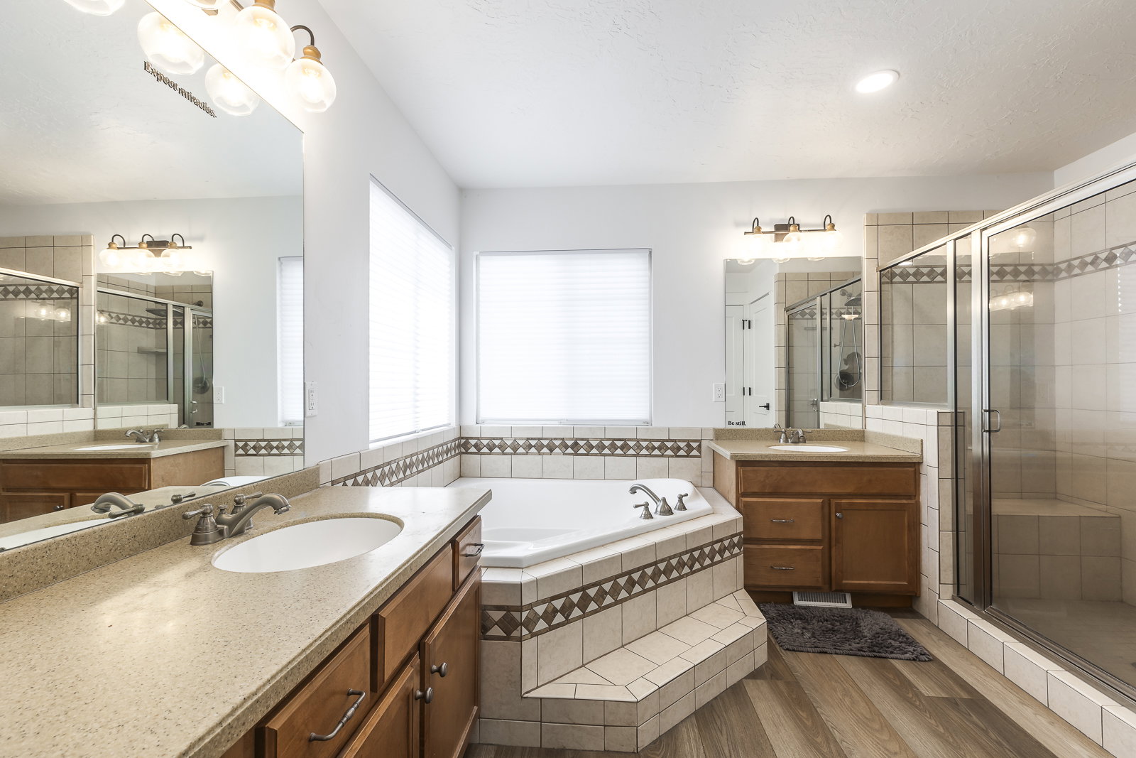 Full bath with a garden tub, a stall shower, two vanities, and light wood-style floors