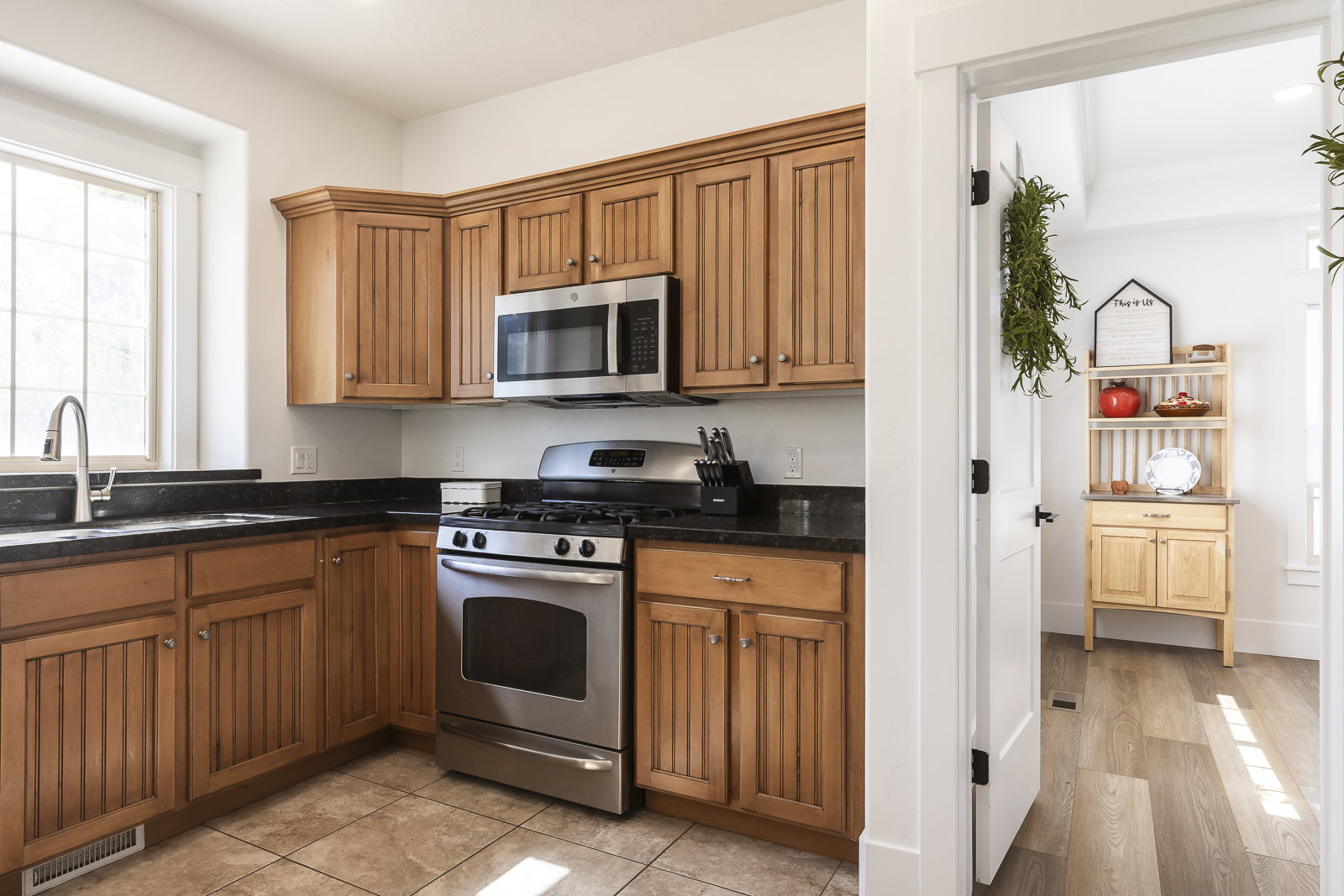 Kitchen with stainless steel appliances, wood finish cabinetry, and dark stone counters