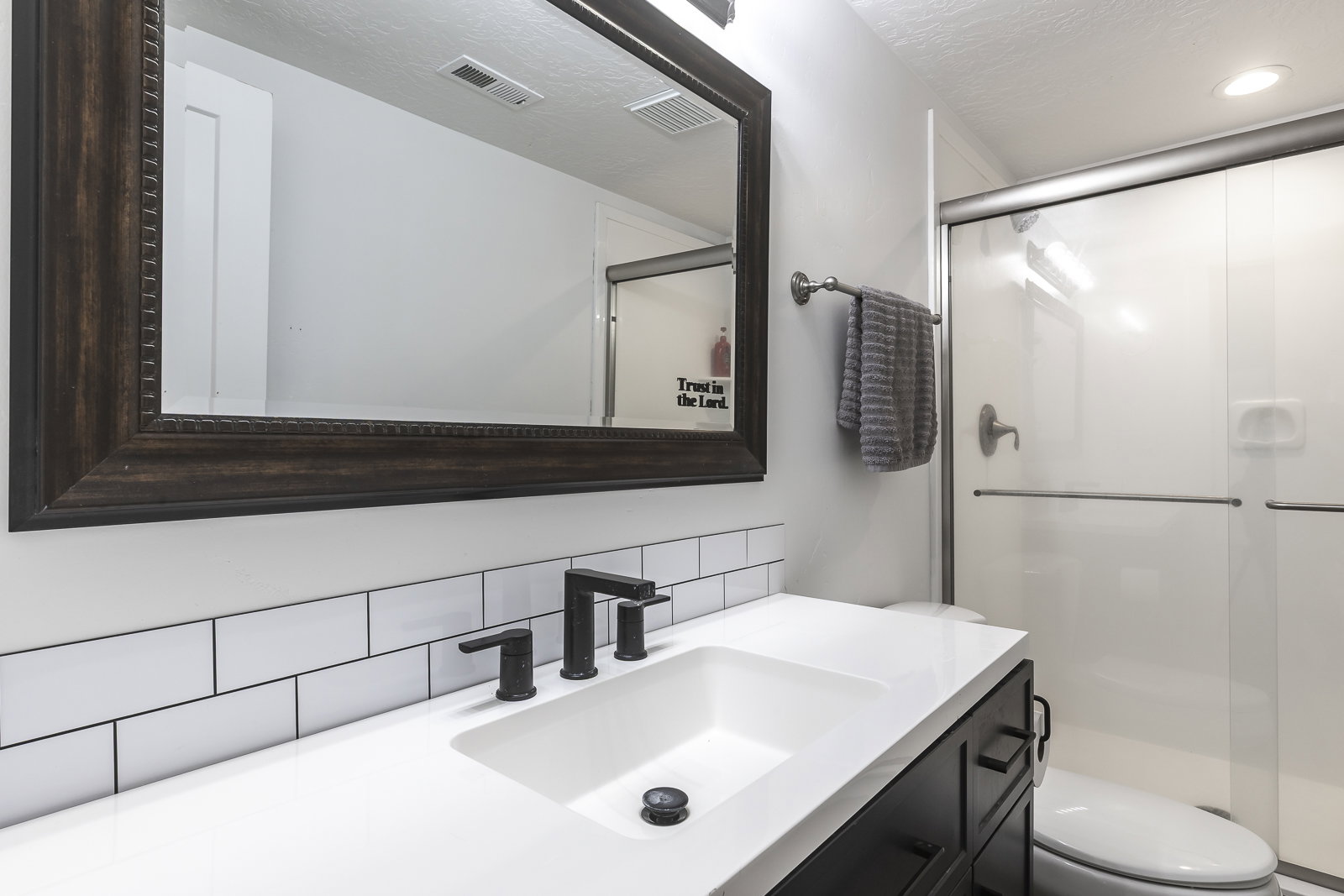 Full bath featuring vanity, a shower stall, decorative backsplash, and a textured ceiling