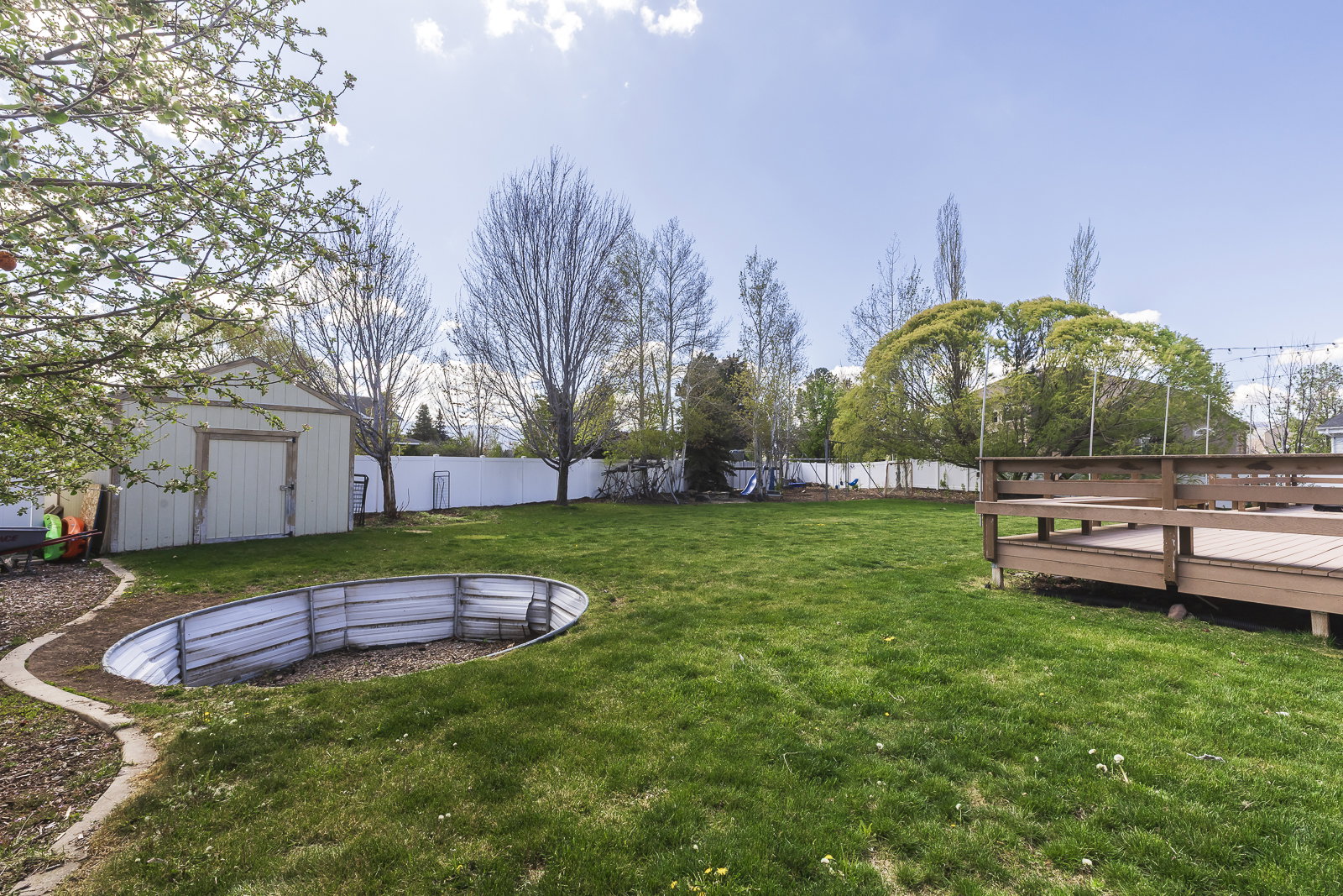 Fenced backyard featuring an outbuilding and a wooden deck