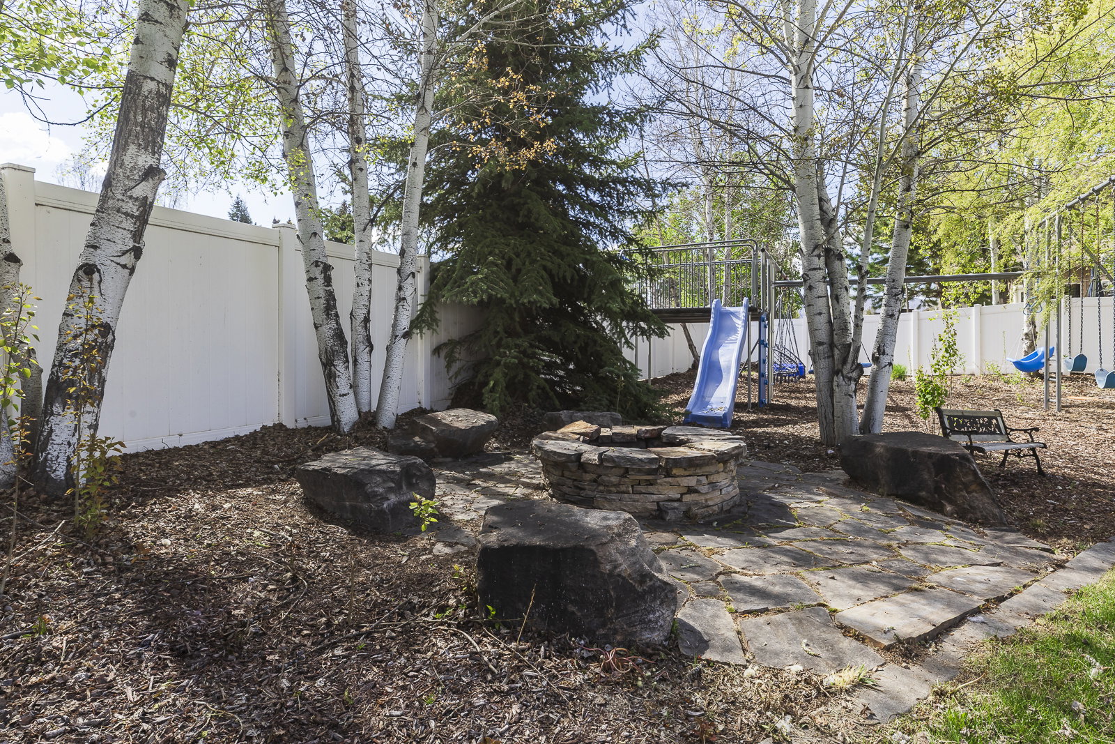 Fenced backyard featuring a fire pit and a playground