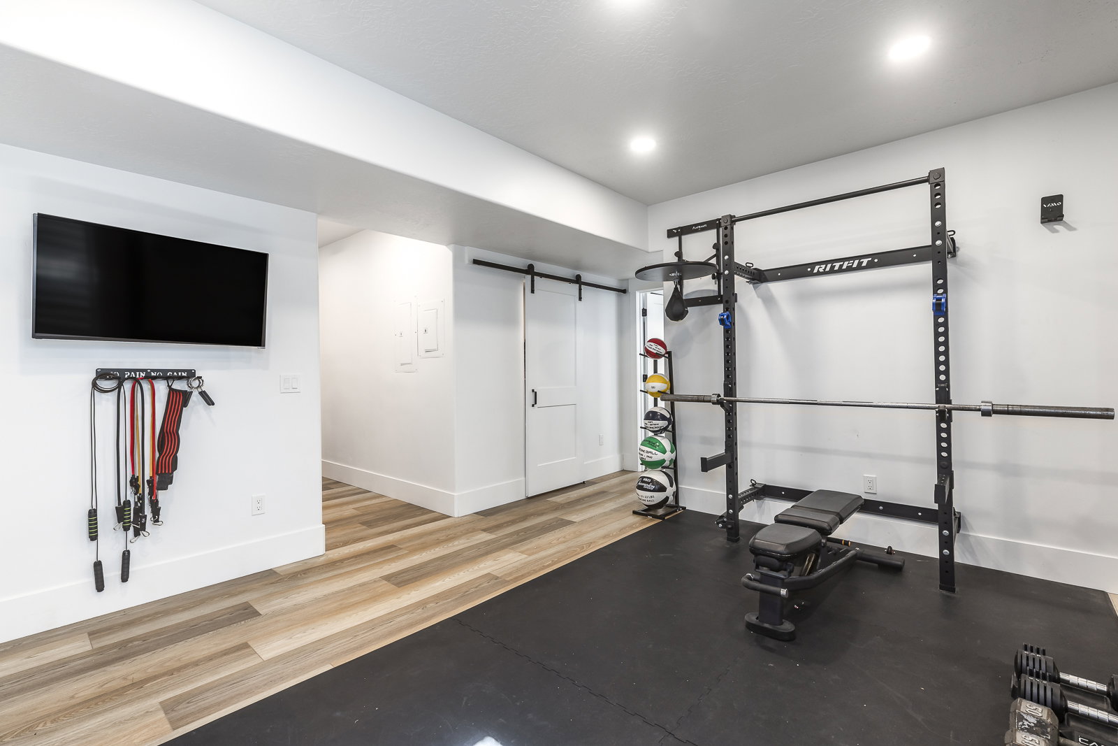 Workout area featuring light wood-style floors, a barn door, and recessed lighting