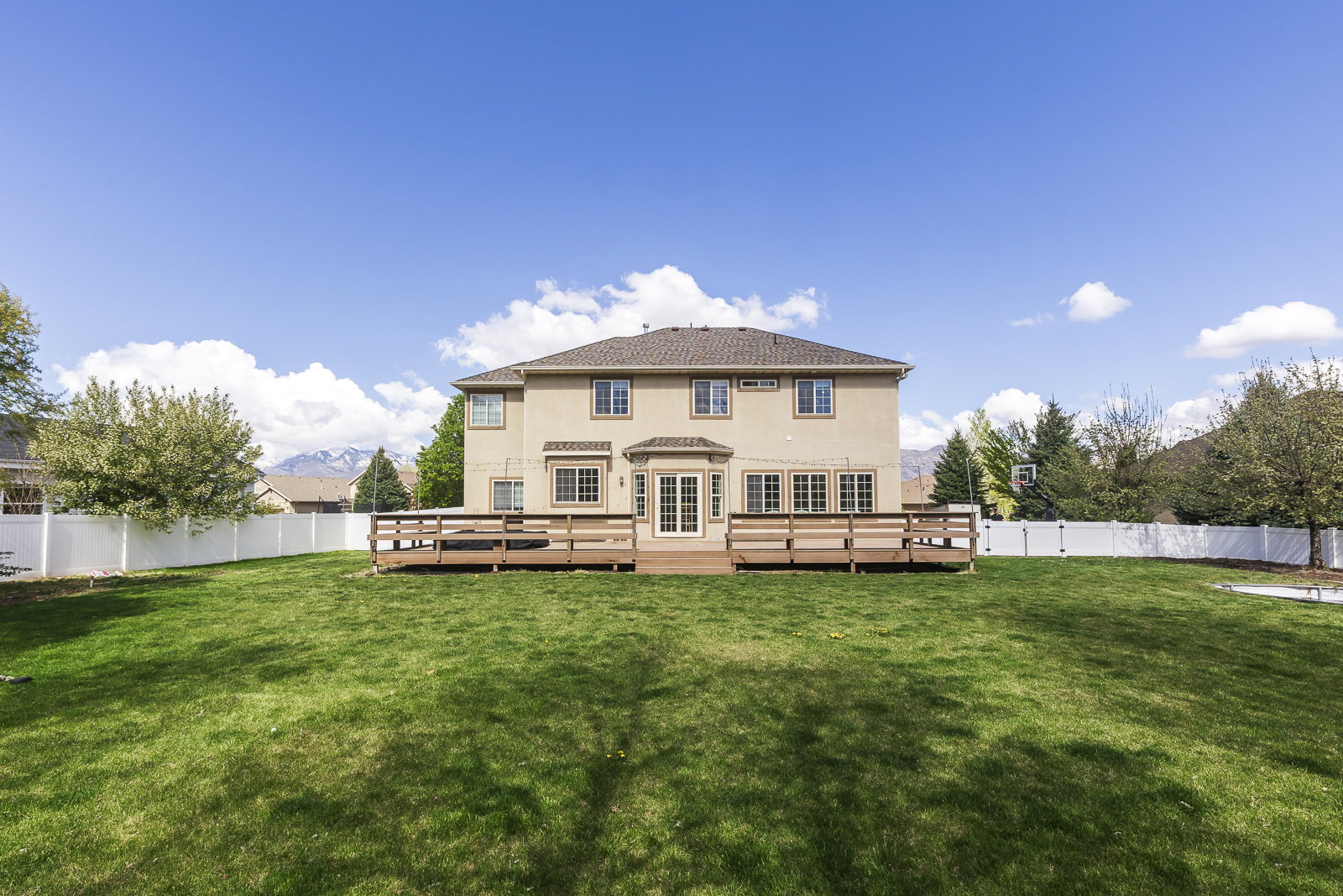Rear view of property with a fenced backyard, a deck with mountain view, and stucco siding