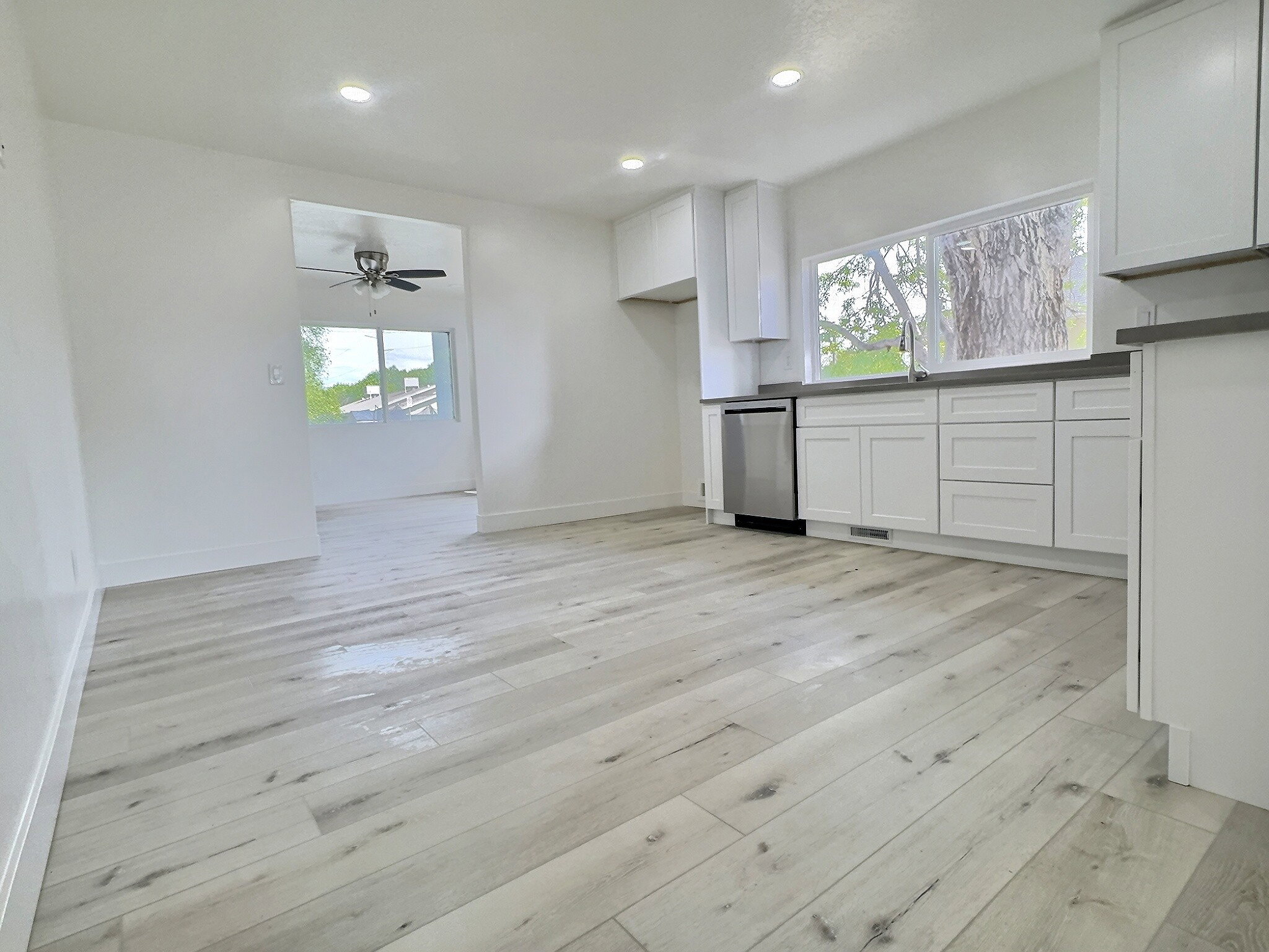 Kitchen featuring white cabinetry, light wood-style flooring, stainless steel dishwasher, ceiling fan, and recessed lighting