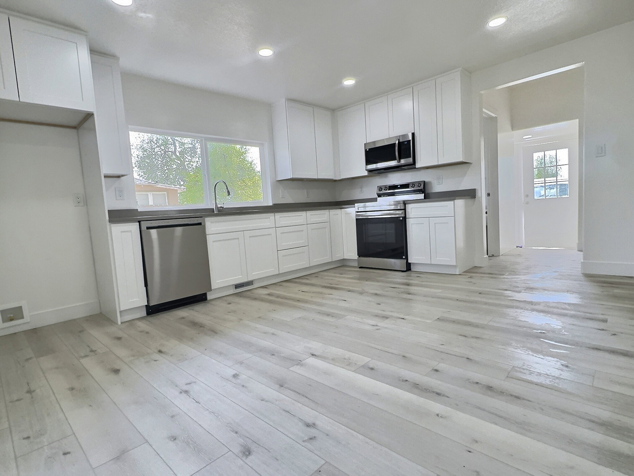 Kitchen featuring white cabinets, stainless steel appliances, dark countertops, and recessed lighting