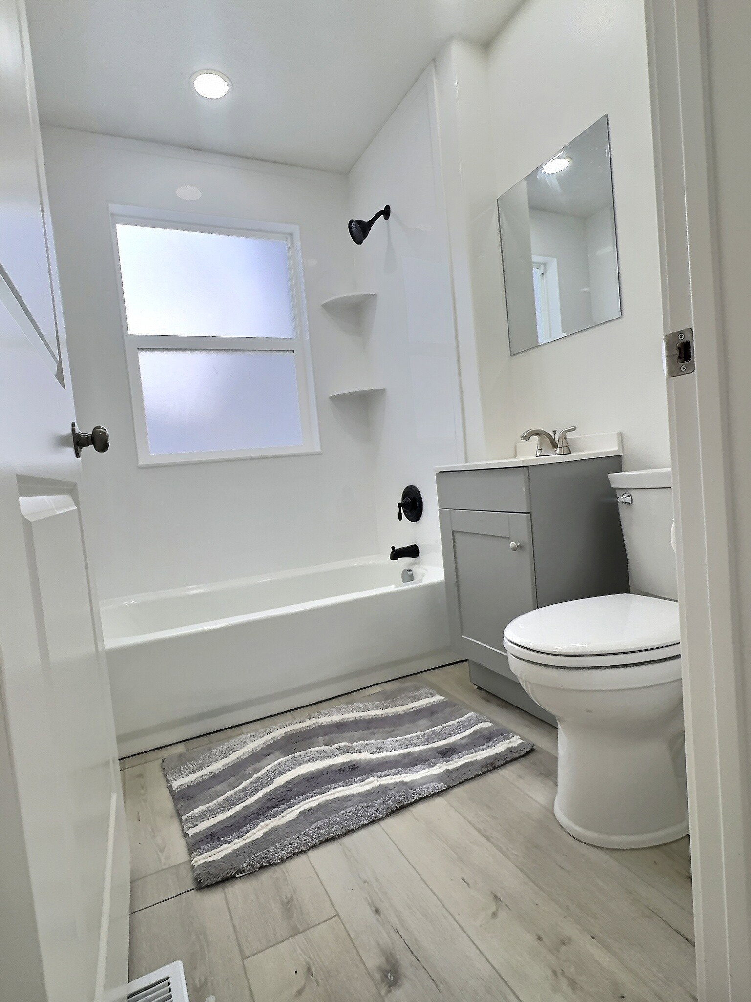 Bathroom featuring vanity, bathing tub / shower combination, and light wood-type flooring
