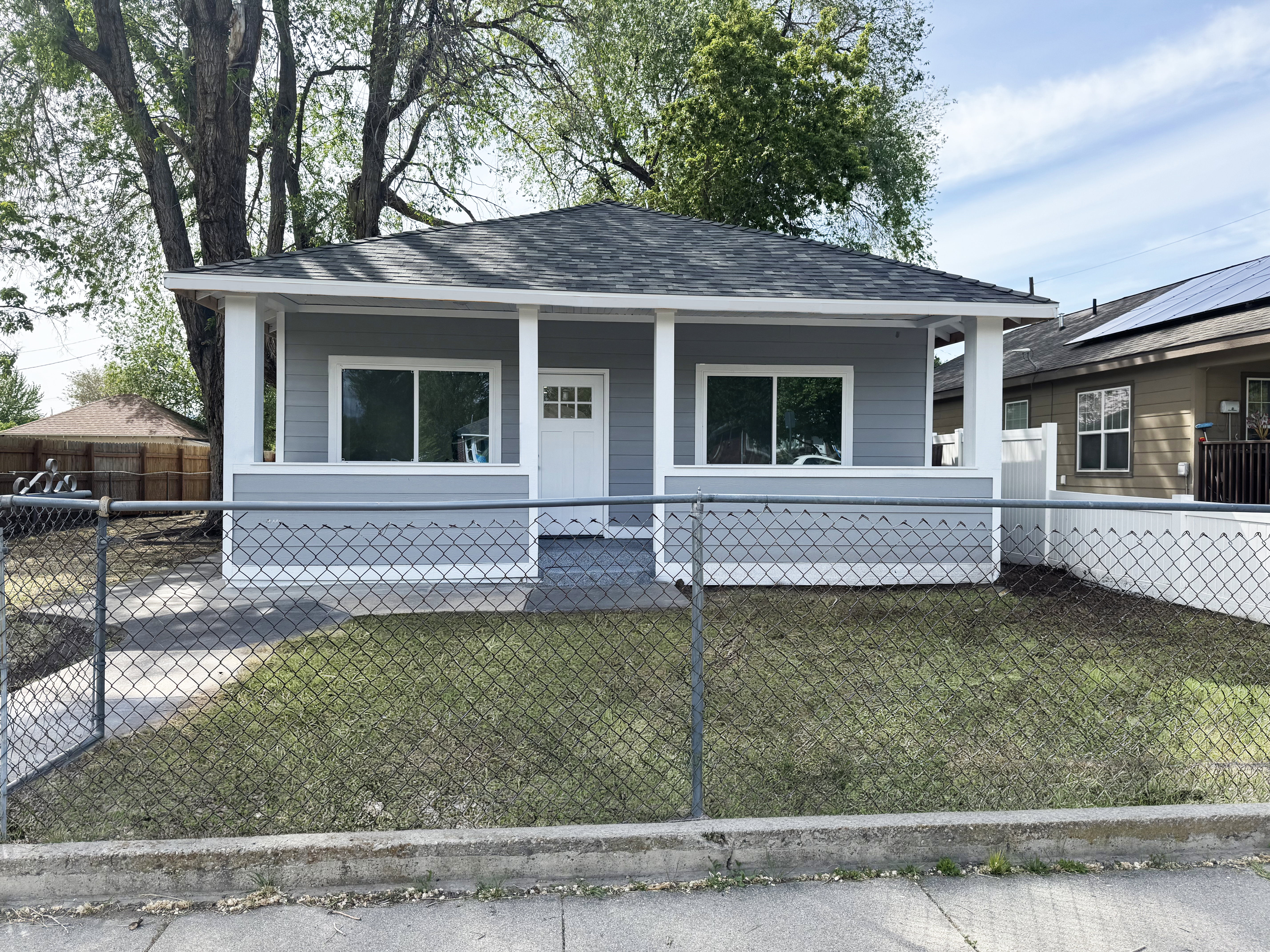 View of front facade featuring a shingled roof, a porch, and a fenced front yard