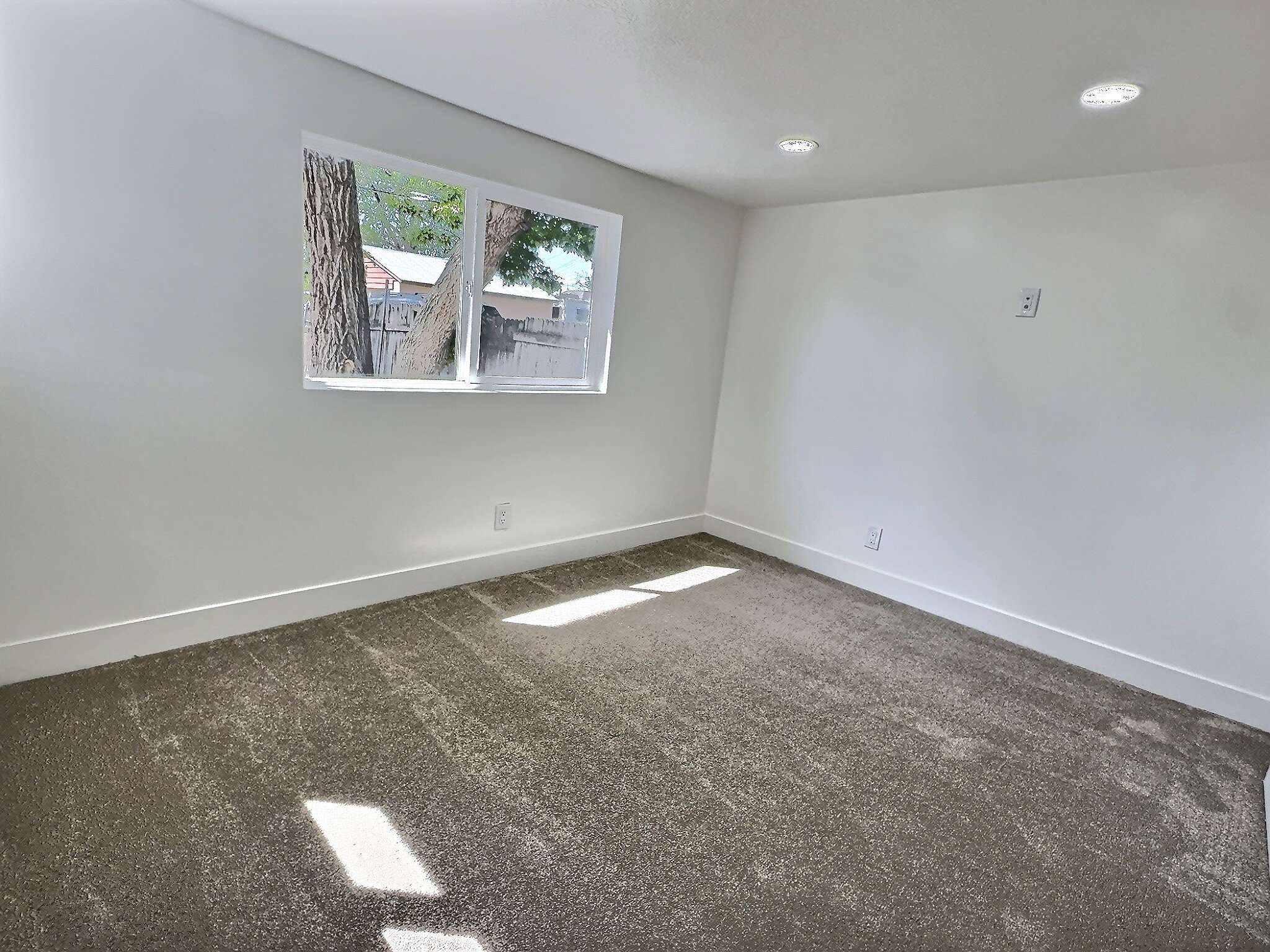 Unfurnished room featuring dark colored carpet and baseboards