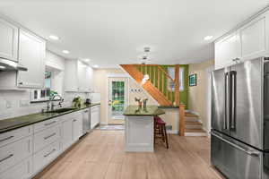 Kitchen featuring stainless steel appliances, white cabinets, tasteful backsplash, and a breakfast bar area