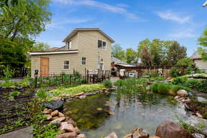 Back of property featuring a garden pond and a fenced backyard and garden beds