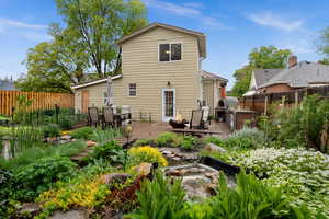 Rear view of property featuring beautiful perennial flower beds, an outdoor kitchen / dining area, and a deck