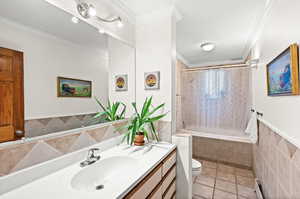 Freshly painted main floor full bathroom with tile walls, tiled shower / bath combo, vanity,  and crown molding