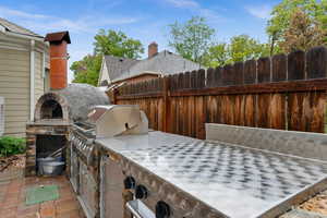 Outdoor kitchen with wood burning pizza oven, gas grill and cook top