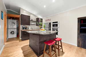 Apartment above garage featuring open kitchen with dark wood cabinets, a center island, a breakfast bar area and stackable washer and dryer