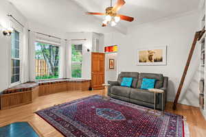 Living area with a ceiling fan, light wood-type flooring, beam ceiling, and crown molding