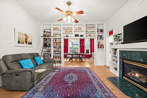 Main floor family room featuring built in shelves, gas fireplace, a ceiling fan, light wood floors and open to the formal dining room
