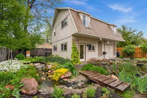 View of two car garage with one bedroom apartment above, water feature and flower beds