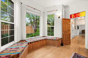 Main floor family room south facing bay window with window seat, with light wood flooring, wood pane door with colored glass transom