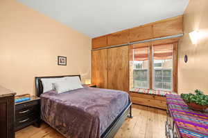 Main floor bedroom with light wood finished floors north facing window with a window seat